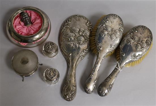 An Edwardian three piece silver brush and mirror set with Reynolds Angel decoration, a George V silver mounted glass